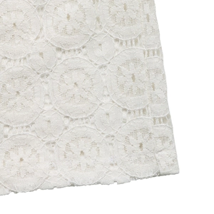 Detailed close-up of white floral lace fabric with circular hollow embroidery patterns