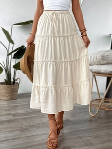 Close-up of tiered white maxi skirt featuring elastic waist with drawstring detail