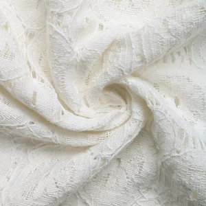 Close-up of white lace fabric detailing the intricate hollow embroidery and soft texture