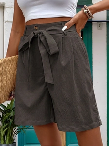 Detail of high waisted paperbag shorts in dark grey with tie-up belt and side pockets