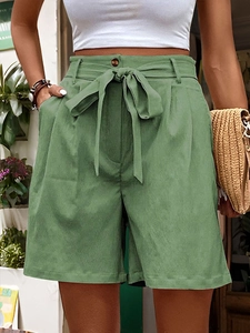 Detail view of high-waisted wide-leg shorts with a bow tie belt and brown button in sage green