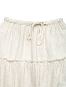 Detail of ivory tiered skirt featuring an elastic waistband and decorative drawstring tie