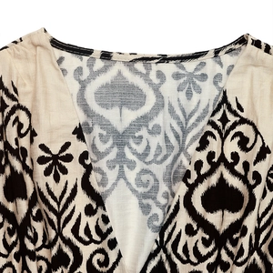 Detail of V-neckline on beige dress with black ethnic Ikat patterns and linen texture