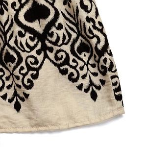 Detailed view of the ethnic black print on natural beige cotton-linen fabric with hem stitching