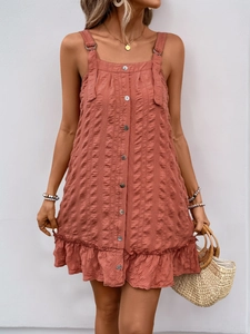 Detail showing the rust red dress's textured fabric, buttons, and ruffle hem details