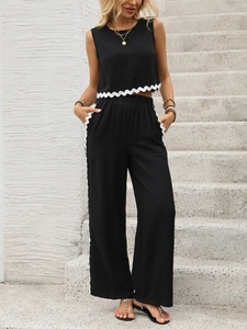 Détail d'un haut sans manches noir et d'un pantalon large avec dentelle ondulée