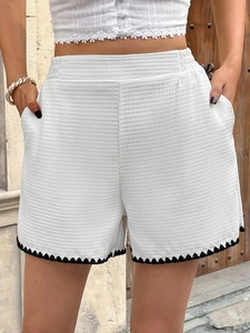 Detail of white waffle texture shorts with black wavy crochet trim and elastic waistband