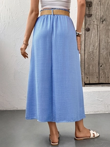 Detail view of light blue linen midi skirt featuring slub texture and woven straw belt
