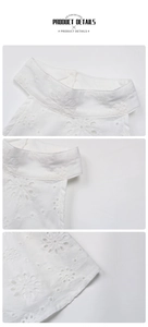 Detail view of white sleeveless top showing exquisite floral embroidery and high neckline