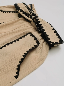 Detail of beige high-waisted shorts with black wave embroidery and drawstring waist