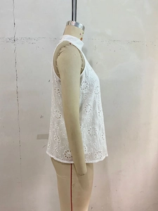 Detail of white sleeveless top featuring intricate floral eyelet embroidery and a high neck