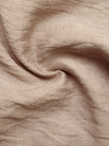 Close-up of lightweight textured fabric with vertical pleats and soft drape detail
