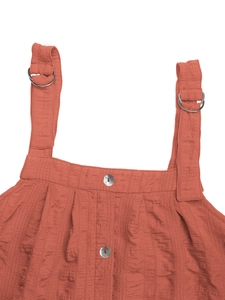 Detail of red-brown textured dress featuring metallic D-rings and pearl button accents