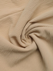 Close-up of light beige crepe fabric showing wrinkled texture and premium material detail