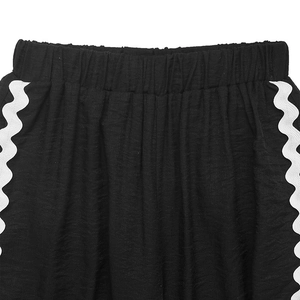 Détail de la taille élastique et bordure zigzag blanche sur pantalon noir