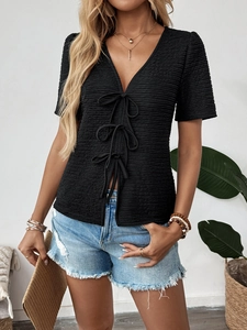 Close-up of black V-neck top with textured knit fabric and three front bow ties