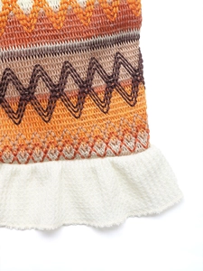 Detail of knit skirt showing orange and brown stripes with white ruffle hem finish