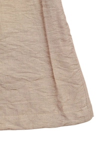 Detailed close-up of light brown cotton linen fabric texture and flat stitched hemline