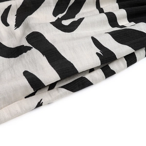 Detailed close-up of abstract black and white zebra print on woven V-neck dress fabric