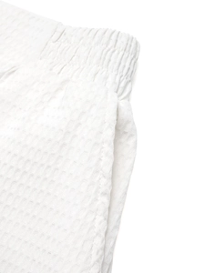 Detail of white waffle knit shorts showing elastic waistband and textured fabric surface