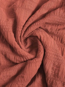 Detailed close-up of smocked texture on brick red strap dress fabric showing fine ruffles
