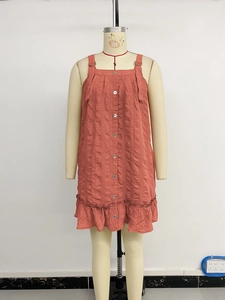 Detail of coral red textured dress featuring front buttons and ruffled hemline
