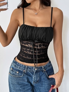 Detail of black slim fit camisole featuring ruched bust, lace cut-outs, and ribbon bow