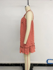 Detailed close-up of coral orange textured fabric with ruffled hem and pleated finish