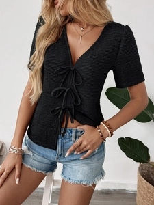 Detail of black textured knit top with V-neckline and three stylish bow tie closures