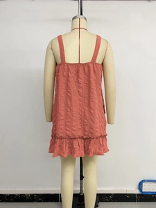 Detail view of the coral red ruffled hem and vertical textured fabric of the summer dress