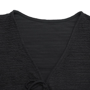 Macro detail of black V-neck top showing unique seersucker texture and delicate bow tie