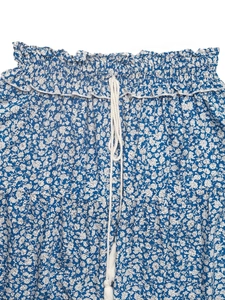 Detailed close-up of elastic ruffled waist with tassel drawstrings on floral mini skirt