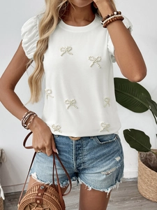 Detail of white cotton T-shirt with pearl bow embellishments and puff sleeves