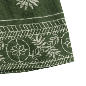 Detailed macro view of olive green cotton fabric with ethnic floral patterns and texture