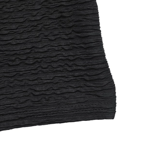 Macro detail of black bubble textured knit fabric with 3D popcorn pleated surface finish
