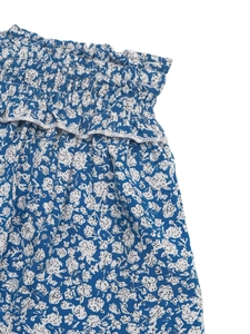 Detail of floral mini skirt featuring elastic ruffled waist and delicate lace trim