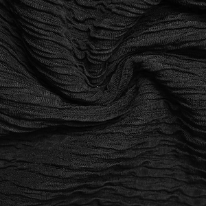 Close-up of black textured knit fabric featuring detailed pleats and irregular wrinkles