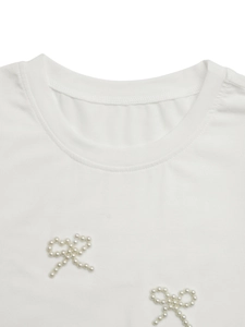 Close-up of beaded pearl bows on a white round neck short-sleeve T-shirt