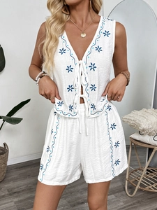 Close-up of bohemian white two-piece set with blue floral embroidery and textured fabric