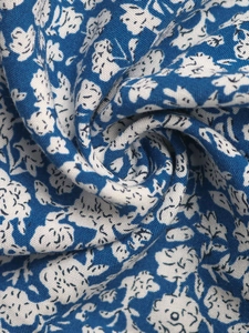 Detailed close-up of blue floral fabric texture with small white flowers on high density cloth