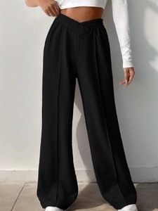 Detail view of high waist black wide leg trousers with V-shaped smocked waistband design