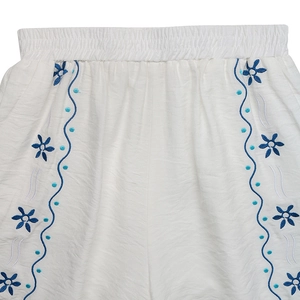 Detailed close-up of blue floral embroidery on white elastic waistband shorts