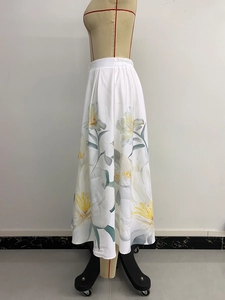 Detalle de falda blanca con estampado de lirios amarillos y botones decorativos