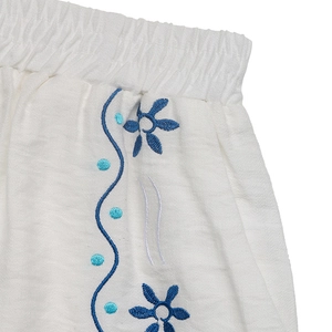 Detail view of elastic waistband on white cotton-linen shorts with blue flower embroidery