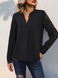 Detail of elegant black blouse featuring intricate lace patchwork on long sleeves