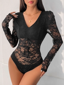 Détail de la dentelle florale noire et des lacets croisés sur un body à manches longues