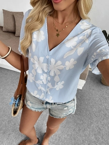 Close-up of white floral embroidery on a blue striped V-neck short sleeve shirt