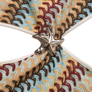 Detail of multi-color crochet knit fabric with a golden starfish metal accessory