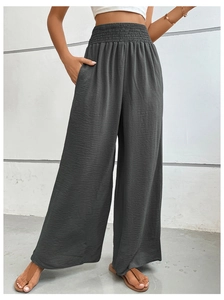 Detail of high waisted smocked waistline on charcoal wide leg trousers with textured fabric