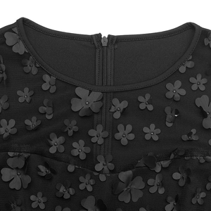 Détail d'une combinaison noire avec appliques florales 3D et empiècement en mesh au col